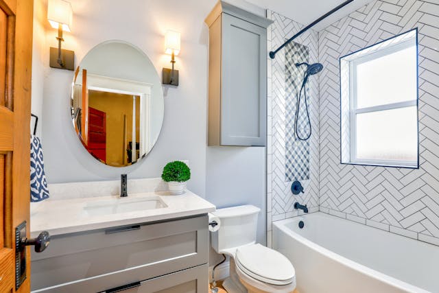 Modern bathroom with a vanity, mirror, shower, and toilet in a white and gray color scheme.