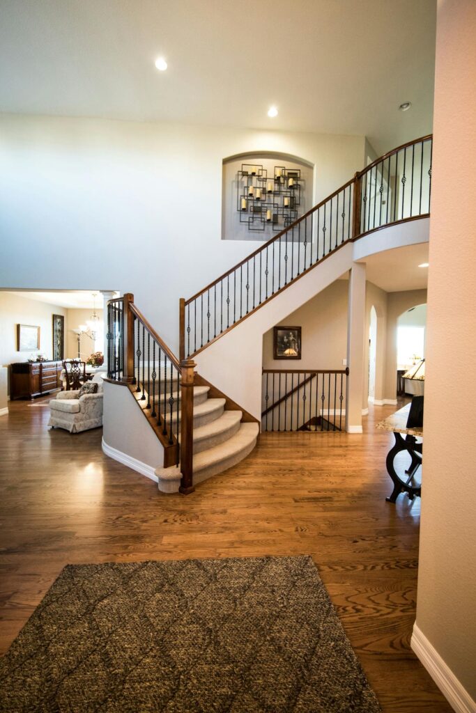 Elegant interior with wooden staircase and upstairs landing, hardwood floors, and neutral walls.