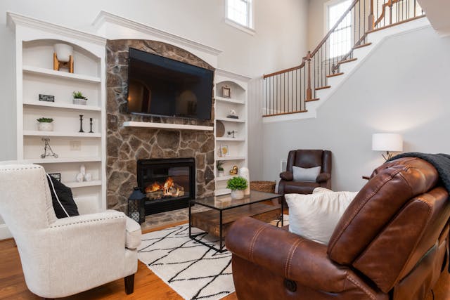 Cozy living room with fireplace, staircase, and elegant furniture.