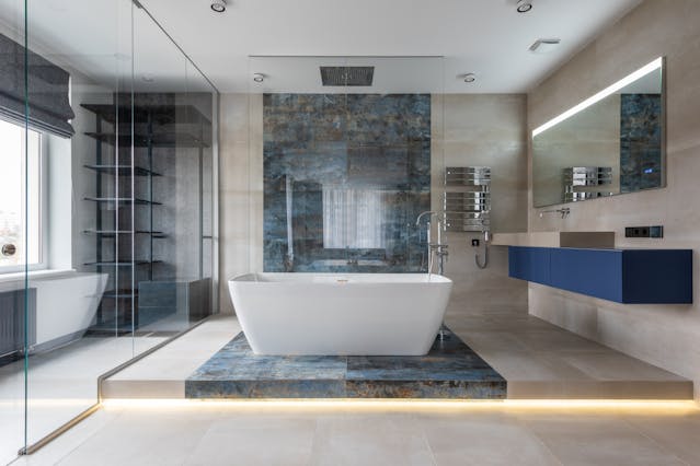 Modern bathroom interior with freestanding tub, glass shower, and LED lighting accents.