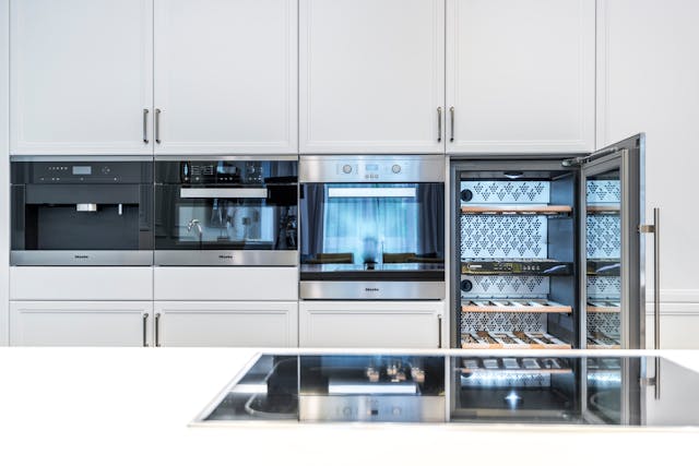 Modern kitchen interior with built-in appliances and an open wine cooler.