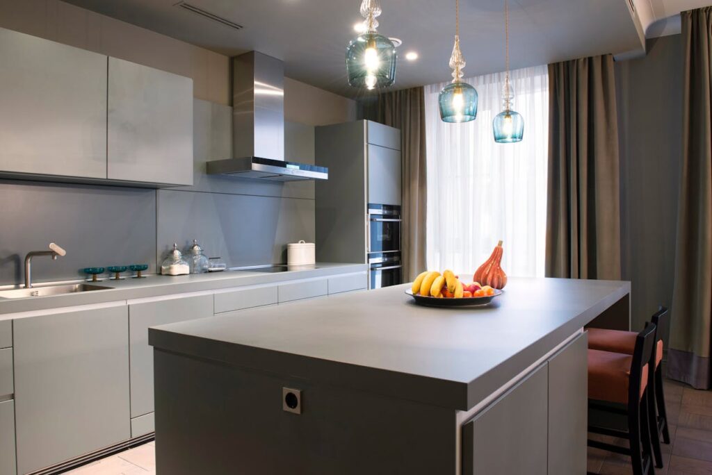 Modern kitchen interior with island, pendant lights, and fruit bowl.