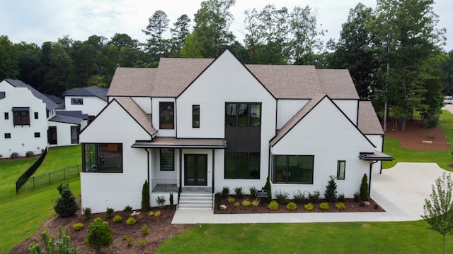 Aerial view of a modern two-story house with a white facade and dark roof.